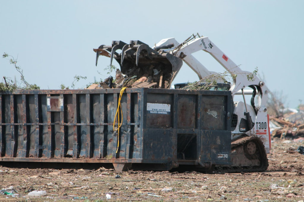 A Picture Of A Dumpster Being Filled By A Bobcat Machine Rented For Dumpster Rent Omaha